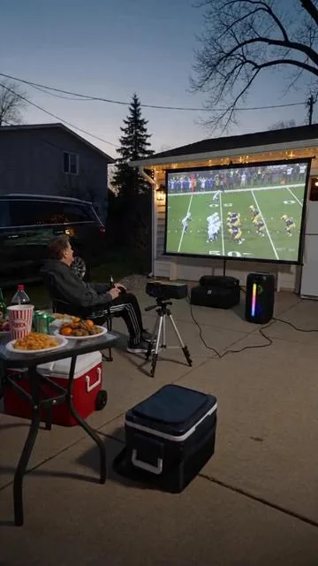 @Mary Deppish sitting in driveway watching a Chiefs football game using the projector on the garage door. Please use a female voice. I am female with a female voice. Also have beer in my hand. Also have a table full of snacks. Have a cooler near by#aicast 